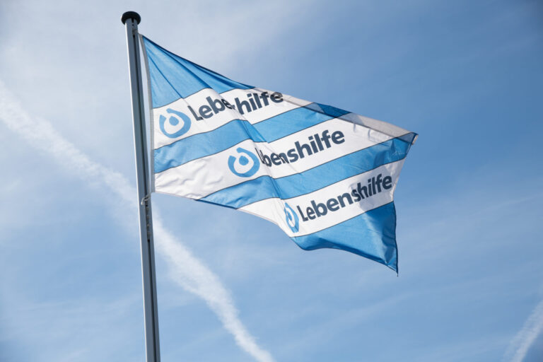 Die Fahne der Lebenshilfe vor einem blauen Himmel